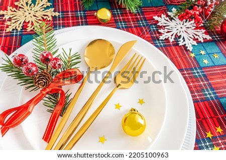 festive serving of the Christmas or New Year's table in the classic style of red and white tones with green spruce branches, Christmas decorations