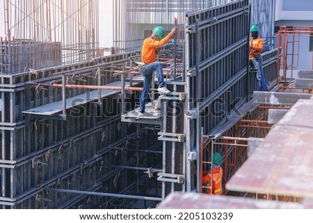Workers are working on construction site, labors wearing vest and safety helmet, construction crews on steel structure work at the building.