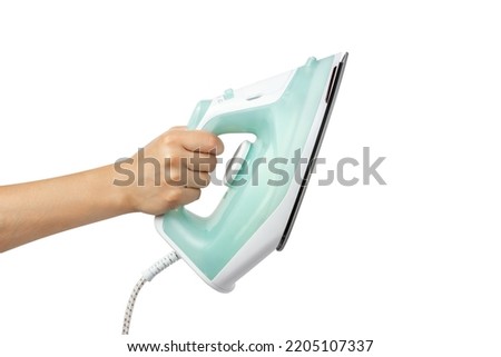 Electric iron in hand isolated on white background. A woman's hand holds an iron. Clothes iron in hand. Royalty-Free Stock Photo #2205107337