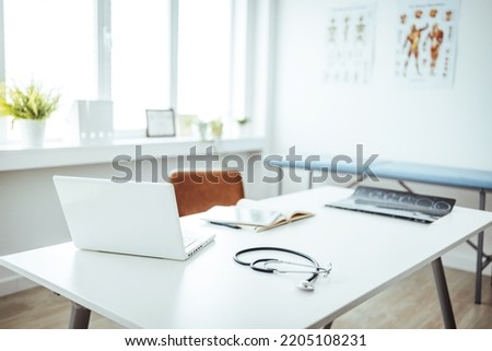 Interior of empty pediatrician office with bed and computer. Doctor's office during the day. Modern white and bright doctor office or medical office interior design with computer  Royalty-Free Stock Photo #2205108231