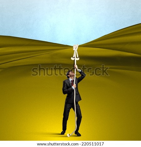 Young businessman pulling curtain with rope. Place for text