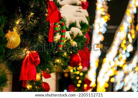 Christmas decoration with green fir tree branches and toys, colorful balls , soxes and red bows in outdoor decor with night city lights on background