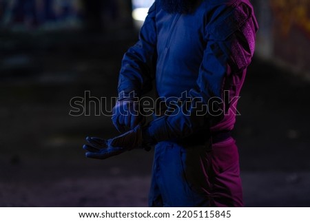 Modern warfare soldier checking navigation, time and other information on a smartwatch. Dark night black background.