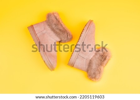 pair of fashionable winter ugg boots on yellow background, new pair Royalty-Free Stock Photo #2205119603
