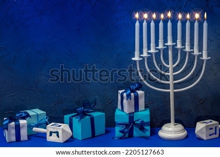 Jewish Hanukkah Menorah 9 Branch Candlestick, dreidel, gift boxes. Holiday Candle Holder, dreidl. Nine-arm candlestick. Traditional Hebrew Festival of Lights candelabra. Background with copy space. Royalty-Free Stock Photo #2205127663
