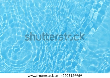 Defocus blurred transparent blue colored clear calm water surface texture with splash, bubble. Shining blue water ripple background. Surface of water in swimming pool. Blue bubble water shining.