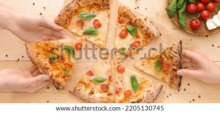 People taking slices of delicious pizza Margherita from wooden table, top view