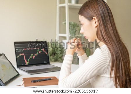 Investor analyzing exchange market, expectation asian young businesswoman thinking, sitting in office, trader on graphic charts on computer, tablet for trading stock, looking at screen with diagrams
