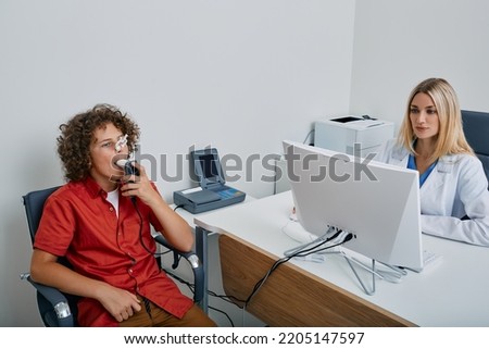 Spirometry of child's lungs. Cute boy with female doctor during spirography test and measuring ventilation of kid lungs with spirometer at medical clinic Royalty-Free Stock Photo #2205147597