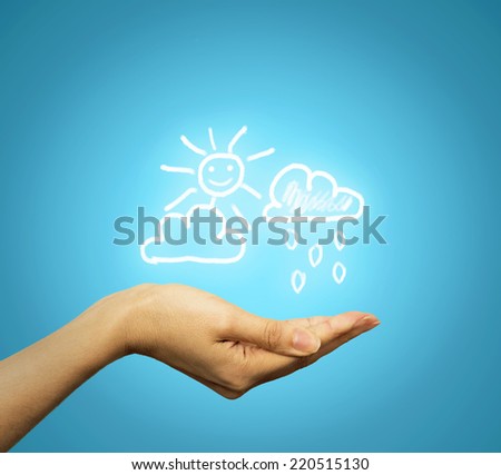 Closeup woman's hand holding cloud sun rain icons, symbols isolated blue indigo color background. Weather forecast prediction concept