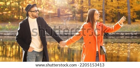 Happy young couple holding hands in beautiful autumn park near lake
