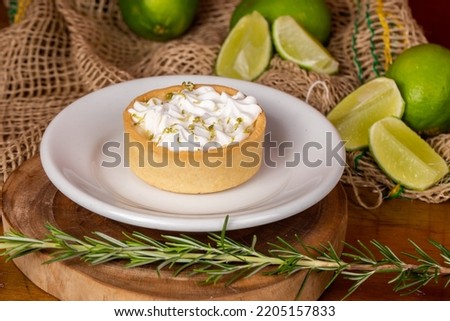 mini lemon pie topped with whipped cream and lemons in the background