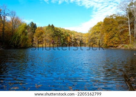 Beautiful autumn landscape with lake and trees. Sunny October day at lake with stunning mirror reflections in water. Sharovka, Ukraine. High quality photo