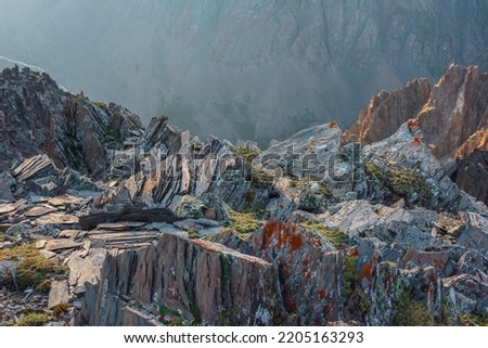Awesome mountain view from cliff at very high altitude. Scenic alpine landscape with edge of precipice with sharp rocks against large mountain wall. Beautiful scenery on abyss edge with sharp stones. Royalty-Free Stock Photo #2205163293