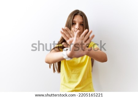 Young brunette teenager standing together over isolated background rejection expression crossing arms and palms doing negative sign, angry face 