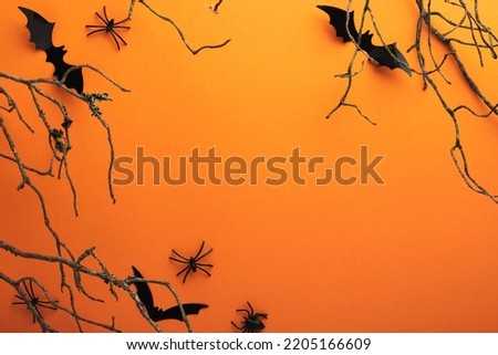 Halloween background. Flock of black bats, spider, pumpkin, skeleton and leaves for Halloween. Black paper bat silhouettes on orange background. Autumn decoration. Halloween concept. Top view.