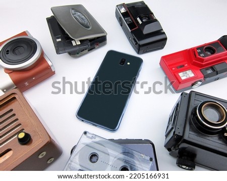 phone in the middle of old cameras and music players on a white background