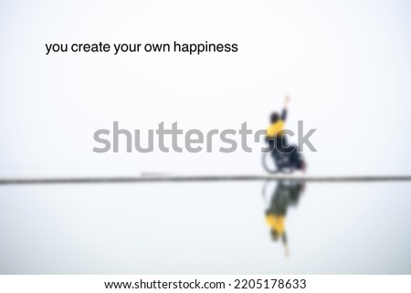A blurred image of a girl sitting on a wheel chair and make a “peace” sign with her hand. A quote saying you create your own happiness.