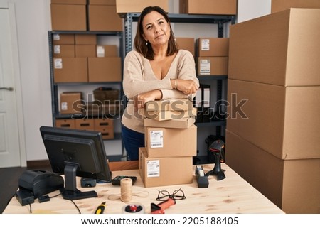 Middle age hispanic woman working at small business ecommerce relaxed with serious expression on face. simple and natural looking at the camera.  Royalty-Free Stock Photo #2205188405