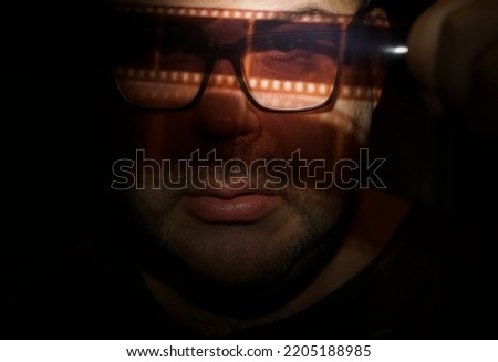 man looks at vintage film in dark room. isolated on black background. Male photograph looking at 35 mm tape. Film photography concept. Film development. vintage hobby. Film photo amateur. archive