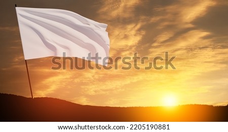 White flag waving in the wind on flagpole against the sunset sky with clouds. White flag is a symbol of surrender. Royalty-Free Stock Photo #2205190881