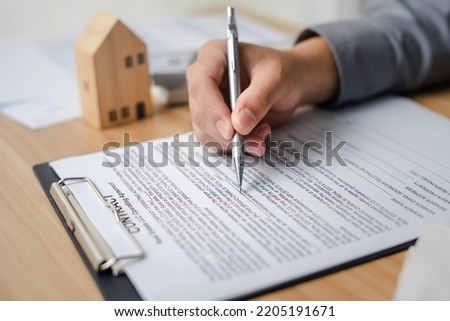 Clients sign real estate contracts through their brokerage agents to purchase a home a profitable investment for a safe residence with a promotion for a loan from a bank to buy property.