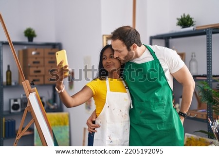 Man and woman artists couple make selfie by smartphone at art studio