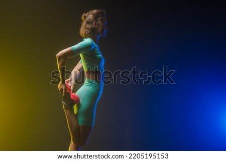 the girl trains on a dark background, modern fitness on a yellow-blue background with a place for text