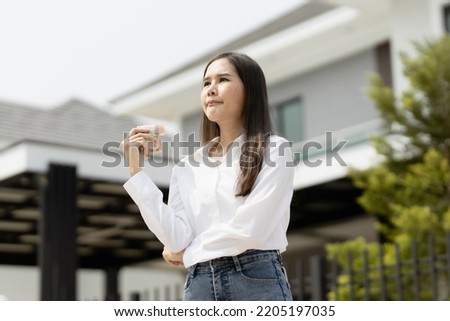 home, money, people concept. Smiling young successful happy business woman holding dollar cash money in hand over house and home background