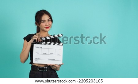 Woman holding clapper board or movie slate on green mint or Tiffany Blue  background.