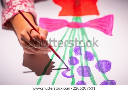 Child's hand  painting a picture in home studio. Selective focus on hand.