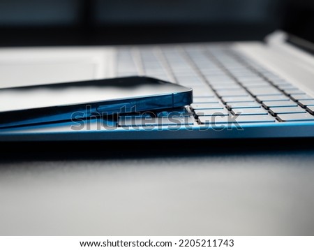Gray laptop keyboard and smartphone close-up. Low angle view of computer key. Selective soft focus.