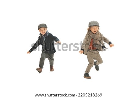 Catch-up. Two preschool age boys, fashionable kids wearing autumn retro clothes strolling isolated over white background. Concept of childhood, vintage summer fashion style. Copy space for ad