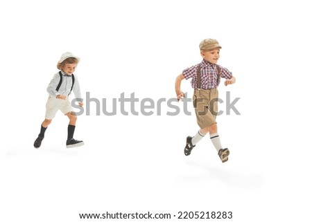 Fun, joy. Two preschool age boys, stylish kids wearing retro clothes running isolated over white background. Concept of childhood, vintage summer fashion style. Copy space for ad