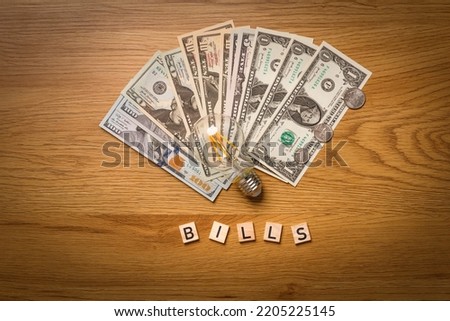 Classic electric light bulb with money scattered on the desk. Photo for Finance and energetic and high electricity bill prices concepts. 
 World economy crisis.