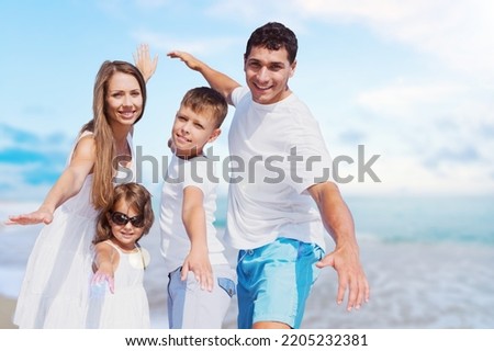 Vacation time. An excited afamily jumping on the beach with a beautiful ocean in the background.