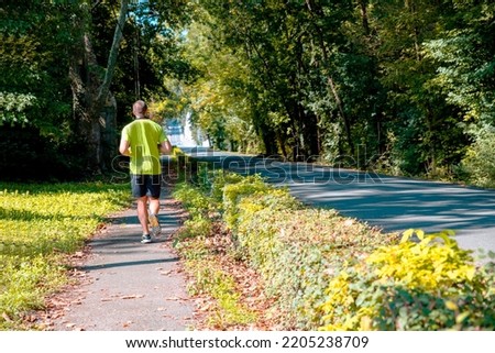 Back of Man jogging on the sidewalk in the city park. Copy space Royalty-Free Stock Photo #2205238709
