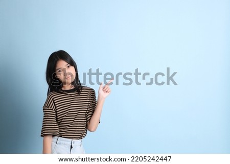 The young Asian girl with brown shirt on the blue background.