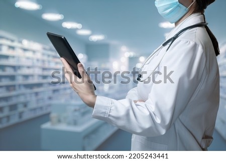 Pharmacist in uniform records medicines in a pharmacy.