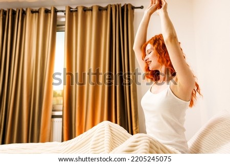 Young woman woke up in the morning in the bedroom by the window with her back.