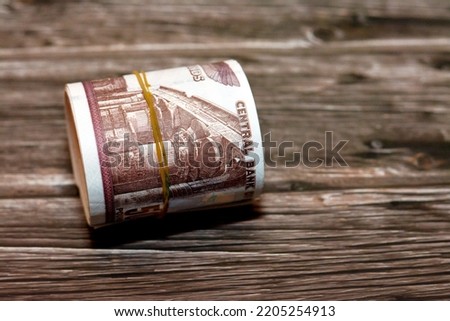 Egypt money roll pounds isolated on wooden background, 50 LE fifty Egyptian pounds cash money bills rolled up with rubber bands with a image of Abu Hurayba Mosque, temple of Edfu and winged scarab