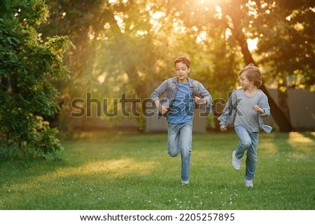 Two boys running and racing each other outdoors in park. Siblings connection	                               Royalty-Free Stock Photo #2205257895
