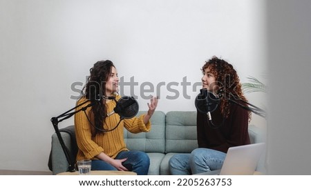 Female host recording radio podcast interview with guest at home office - Main focus on right latin woman face