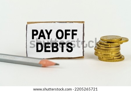 Business concept. On a white background, a pencil, coins and a sign with the inscription - Pay Off Debts