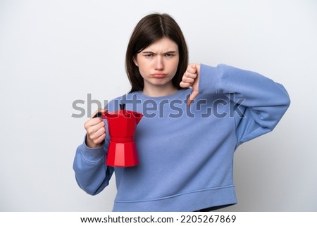 Young Russian woman holding coffee pot isolated on white background showing thumb down with negative expression