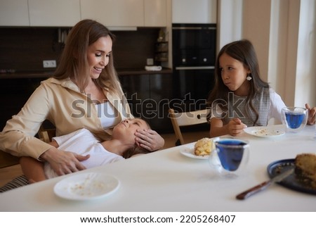 Young mother with a beautiful daughter drinks tea in the kitchen.