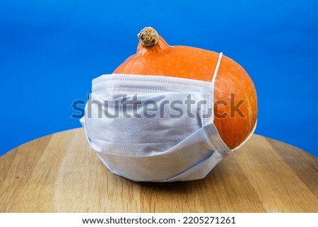 pumpkin wearing a face mask for protection from coronavirus. Halloween 2022 concept. Closeup
