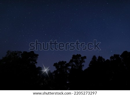 Bright star rising above a dark forest for the Christmas holiday in Raeford North Carolina