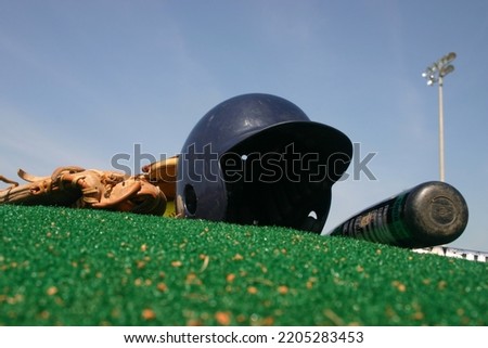 Batters helmet with glove and bat on pitchers mound Royalty-Free Stock Photo #2205283453