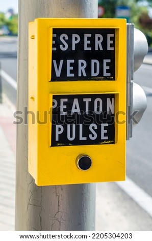 Button on a pedestrian traffic light in Spain, to request that the light turn green. Text translation: "Wait for green" and "Pedestrian press")